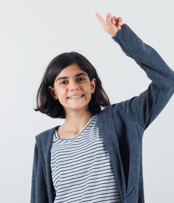 little girl pointing up by raising arm in t-shirt, jacket and looking happy. front view.
