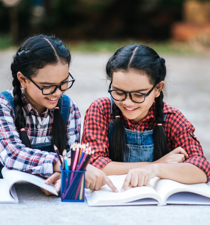 Two students studying together online with a laptop in the park